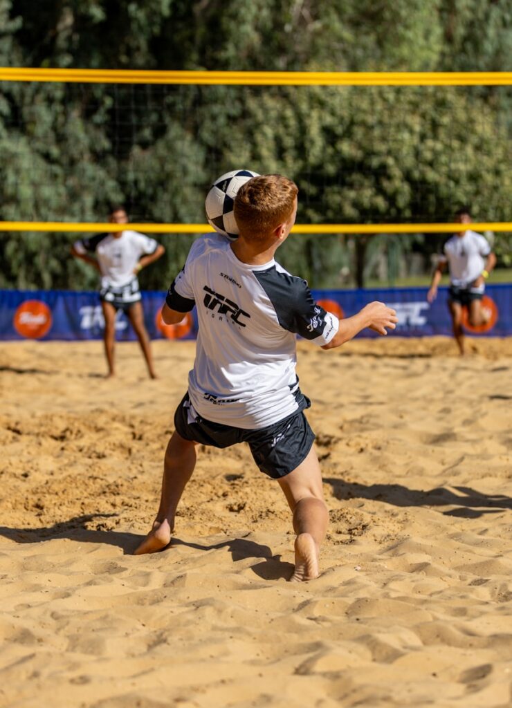 Young man playing sepak takraw on a sandy court